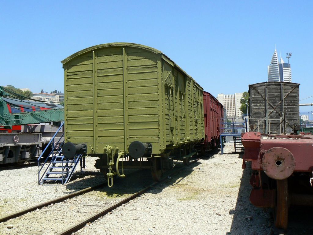 Старые деревянные вагоны на фоне современных зданий.